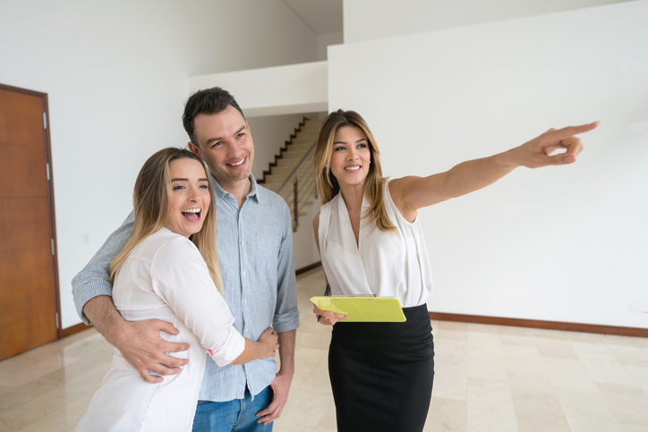 Real estate agent showing a house to a happy couple and smiling while talking